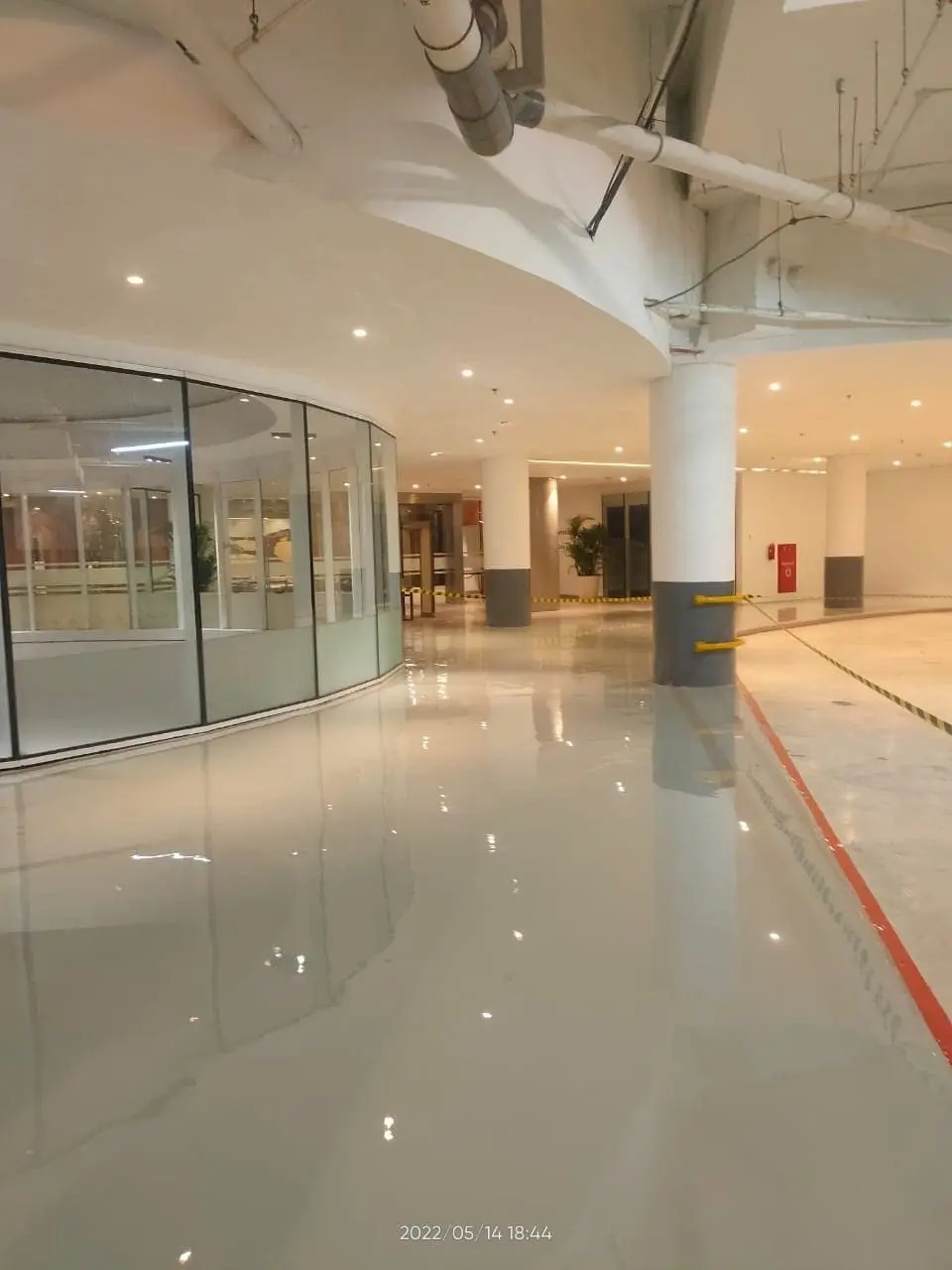 Koridor lobi hotel dengan epoxy self-levelling krem, permukaan memantulkan dinding kaca